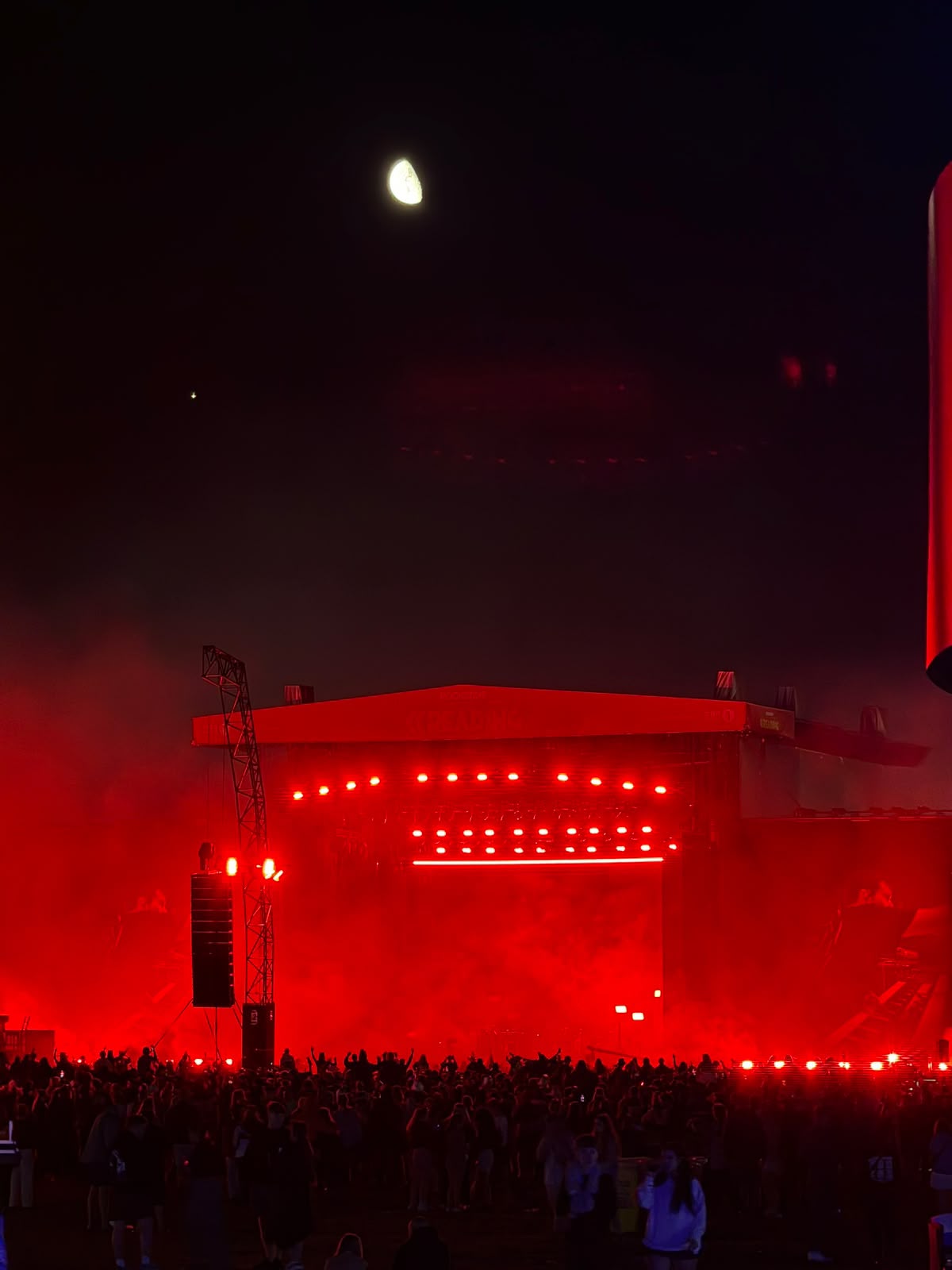 A crowd and stage lit red at a live event