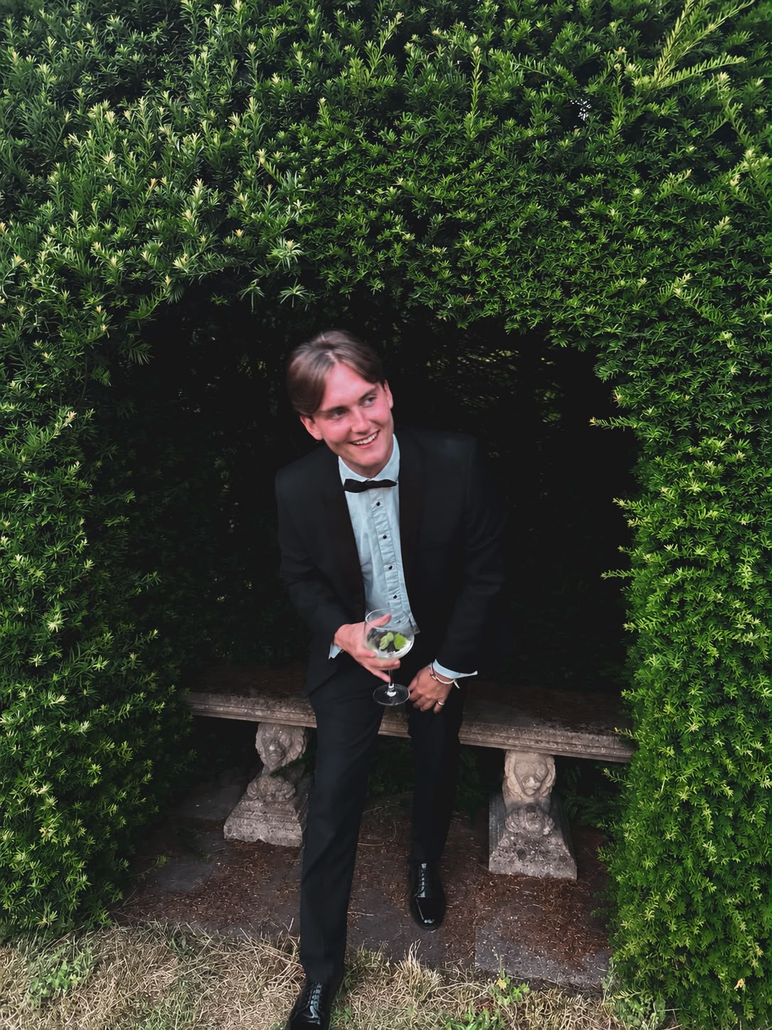 Toby smiling in a garden, dressed in black tie